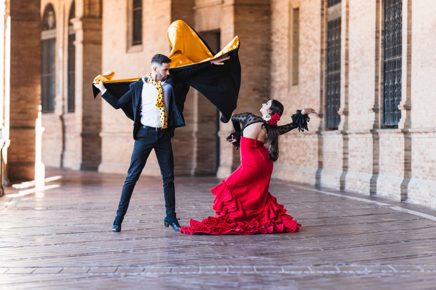 Man and woman in flamenco costume performing a dance outdoors