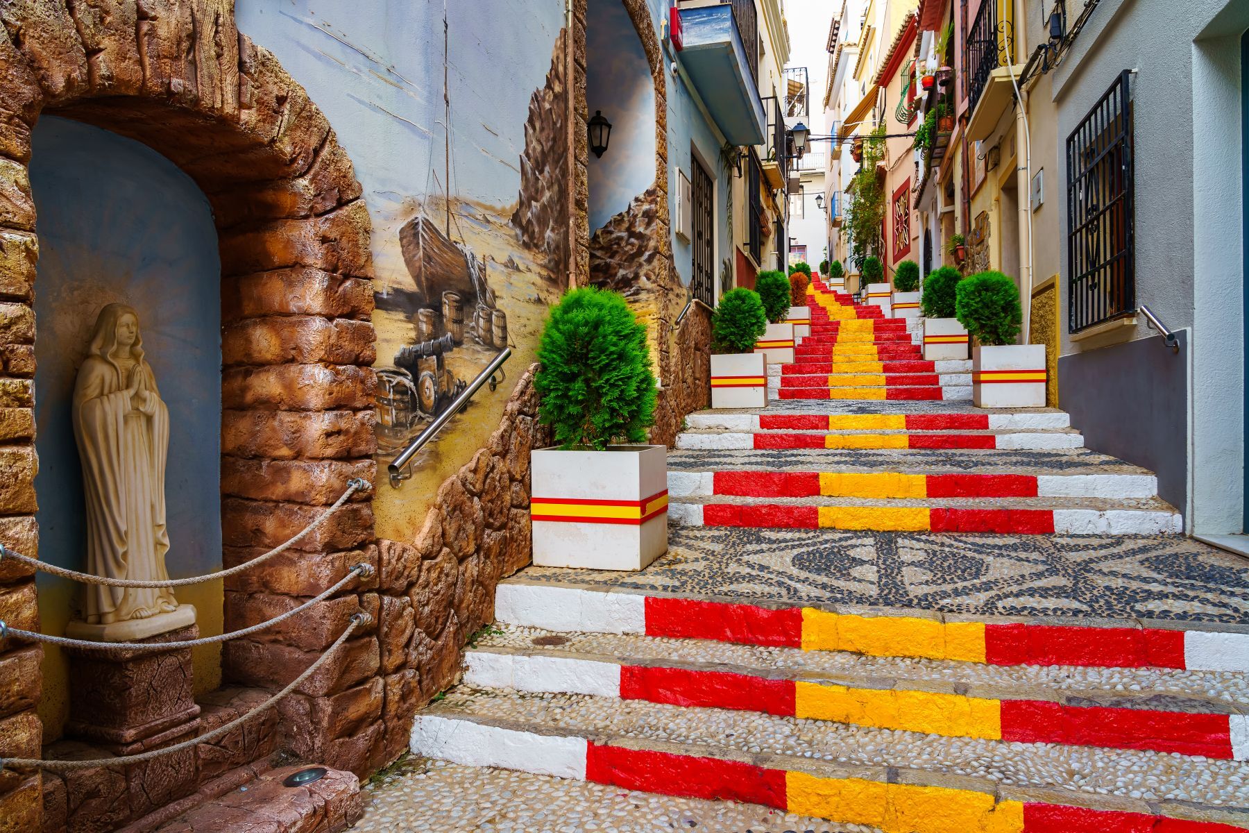 Estrecho callejón decorado con la bandera de España en las escaleras en Calpe Alicante