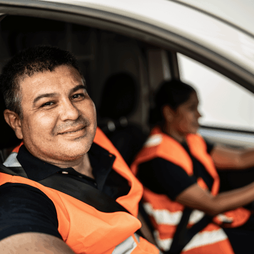 Smiling employee with orange waistcoat in a van