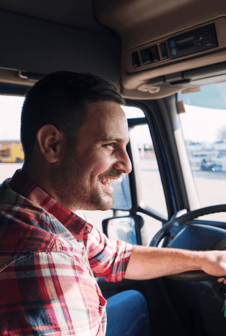 Smiling truck driver with checked shirt at a truck wheel