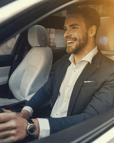 Happy guy in a suit with watch at the wheel in a car