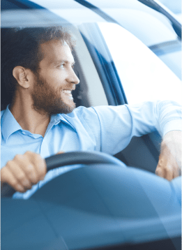 Smiling handsome man with blue shirt at a car wheel