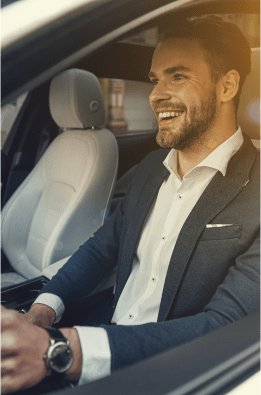 Smiling executive with shirt and watch at a car wheel