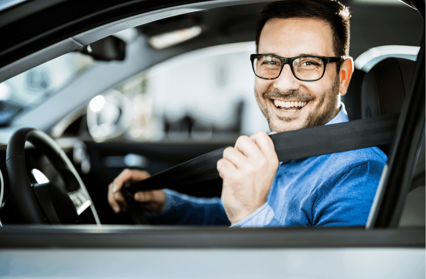 Smiling executive with glasses fastening his seat belt